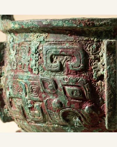 An archaic Chinese bronze ritual vessel with heavy malachite-green encrustation and taotie decoration. — the taotie mask.