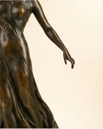 A patinated bronze figure of a dancer on a marble socle, photographed on a warm paper plate. — patina.