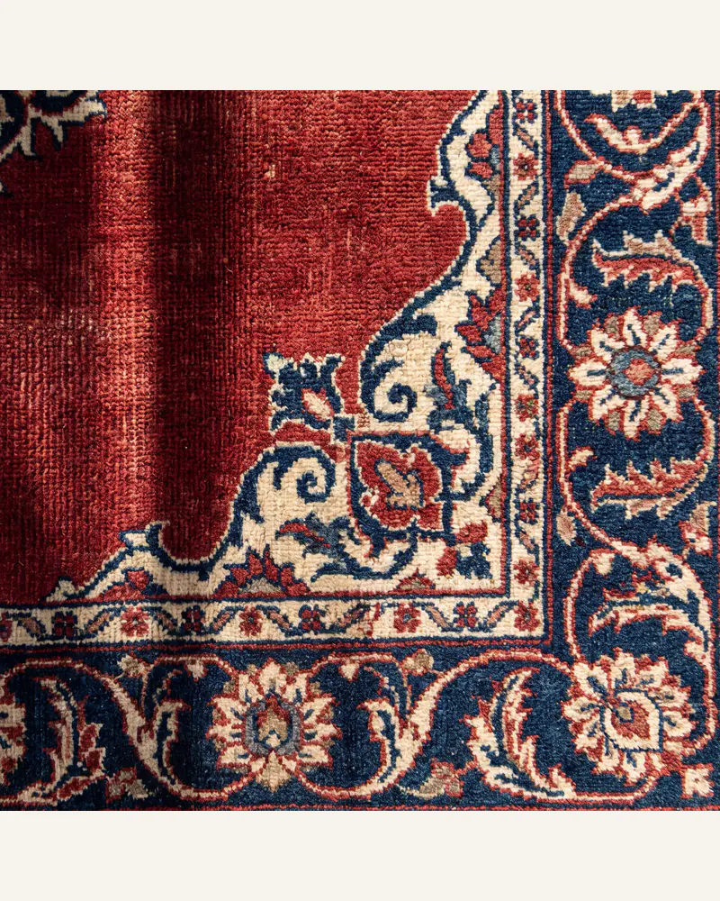 The corner of an antique hand-knotted Persian carpet with a palmette border.