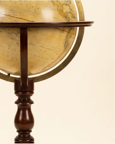 An antique terrestrial library globe on a mahogany tripod stand with a brass meridian ring. — the varnish.