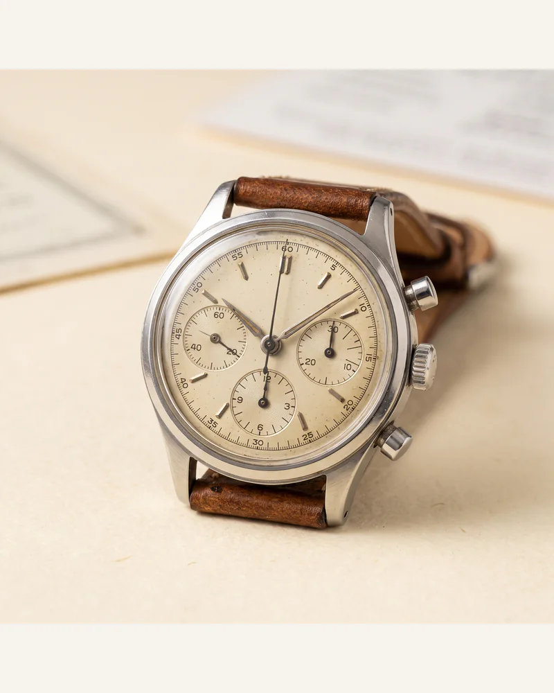 A vintage steel chronograph wristwatch on a worn leather strap.