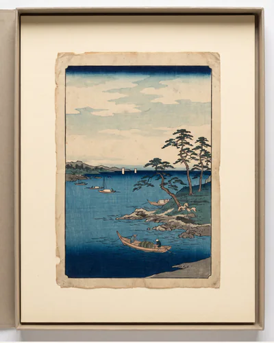 A Japanese ukiyo-e woodblock print of a coastal landscape in Prussian blue, laid flat on a mount board.